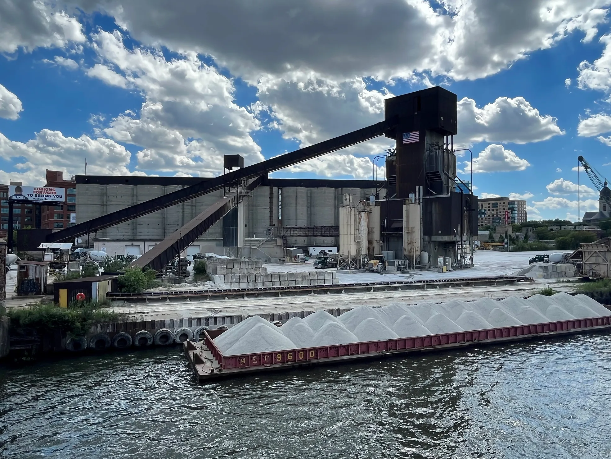 IDOT Approved Concrete Supplier - barge loaded with aggregate at a riverside concrete plant with conveyors and silos