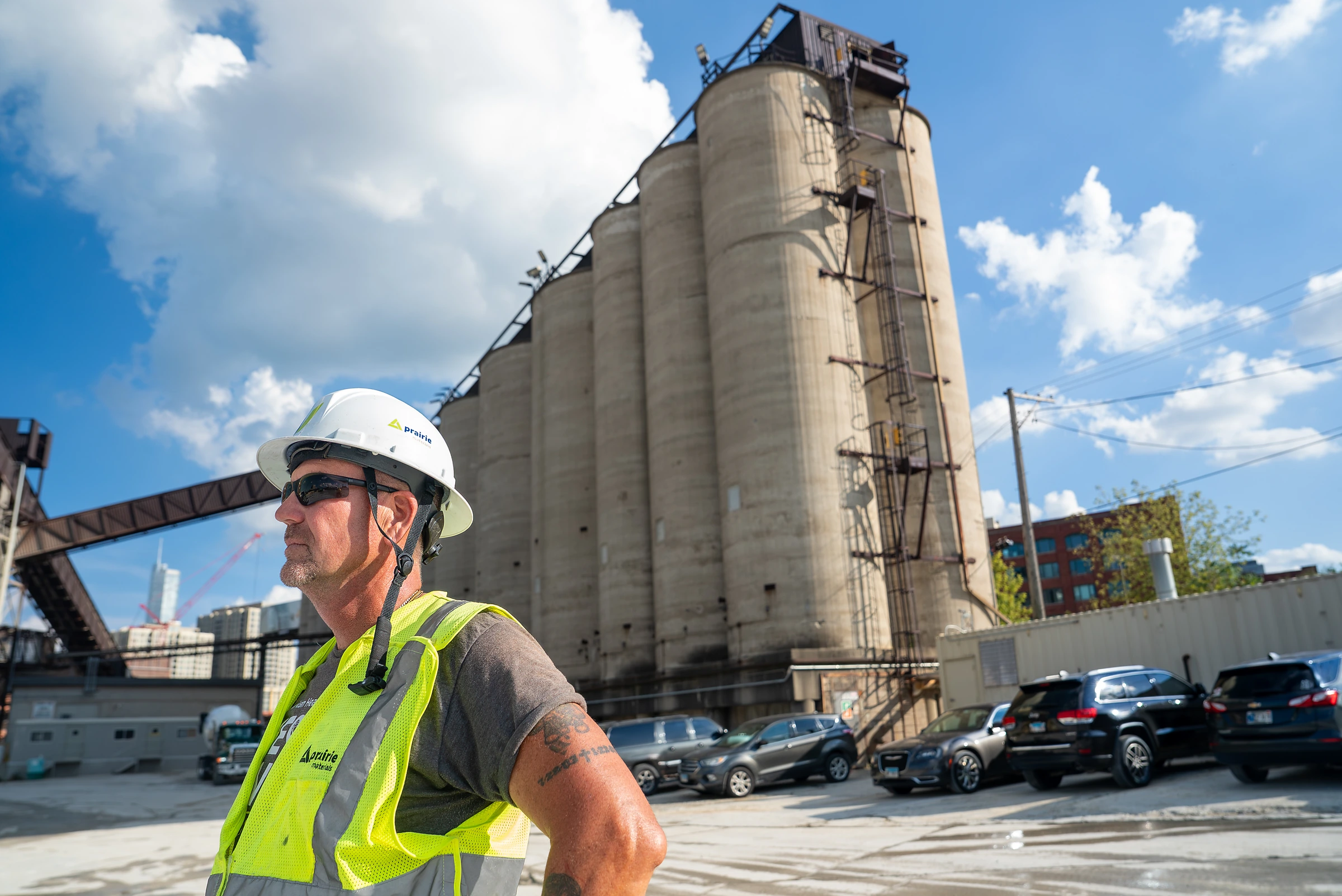IDOT Approved Concrete Supplier - worker in a hard hat and safety vest in front of tall concrete storage silos