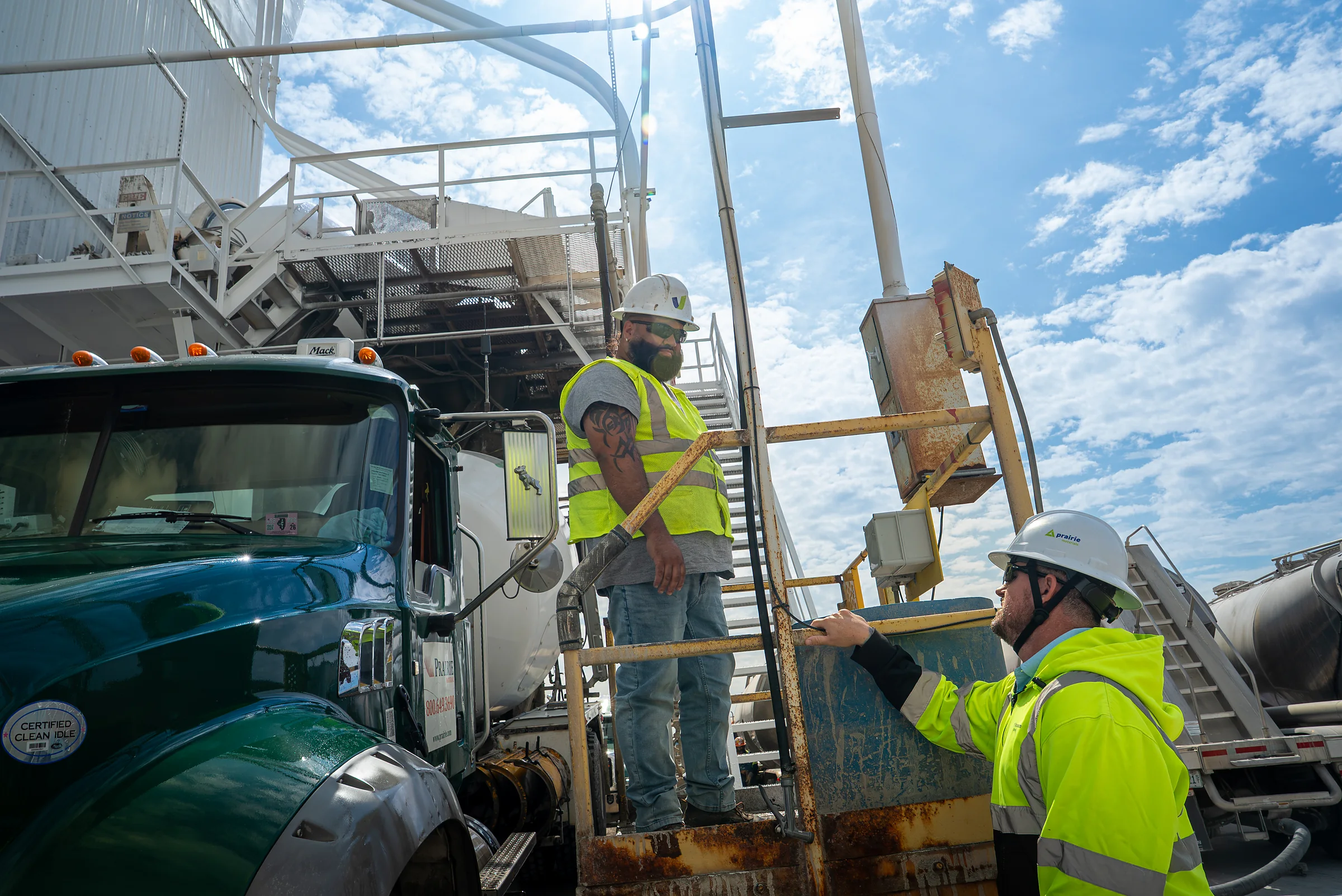 IDOT Approved Concrete Supplier - two Prairie Materials workers in hard hats beside a green mixer truck at a batch plant