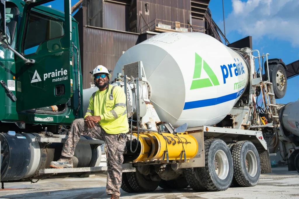 IDOT Approved Concrete Supplier - Prairie Materials driver on the step of a green Prairie mixer truck