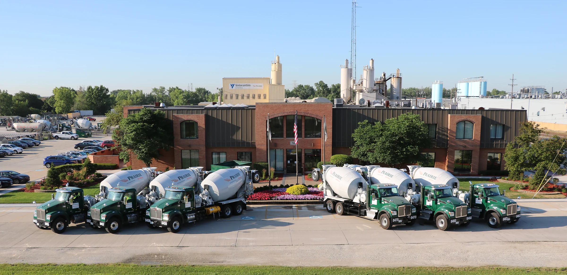 IDOT Approved Concrete Supplier - row of green and white Prairie Materials mixer trucks in front of a brick office
